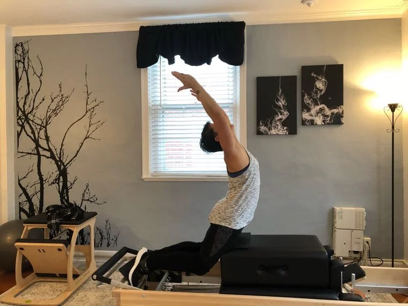Miriam Lundgren kneeling and reaching tall on the reformer